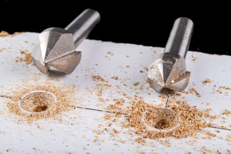 Metal countersink for making holes for screws. Minor jobs in the carpentry workshop. Light background.の写真素材