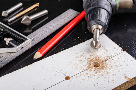 Metal countersink for making holes for screws. Minor jobs in the carpentry workshop. Light background.の写真素材