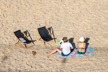 Trzesacz, Zachodniopomorskie / Poland - August, 29, 2020: Two sunbeds and people relaxing on the beach. Young people are resting by the Baltic Sea. Summer season.のeditorial素材