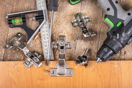 Installation of furniture hinges in a chipboard. Minor carpentry work when assembling furniture. Place - workshop.の写真素材