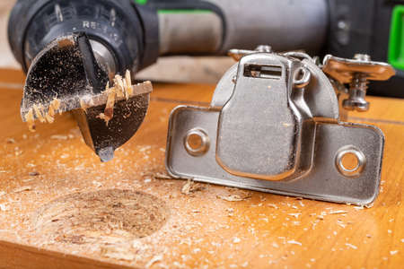 Installation of furniture hinges in a chipboard. Minor carpentry work when assembling furniture. Place - workshop.の写真素材