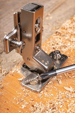 Installation of furniture hinges in a chipboard. Minor carpentry work when assembling furniture. Place - workshop.の写真素材