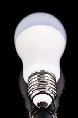 LED bulb on a dark table. Modern LED lighting. Black background.の写真素材