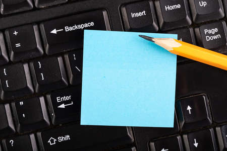 A colorful sheet of notes on a computer keyboard. Place for notes at the computer. Dark background.の写真素材