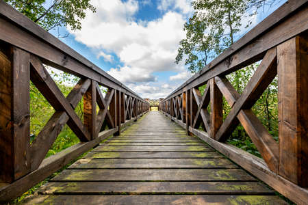 Wooden bridge in the forest with a sturdy railing. A walking area for pedestrians. Summer season.の写真素材