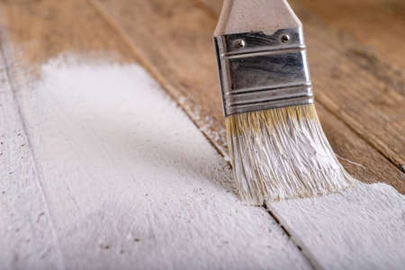 Painting raw wood with white paint. Minor painting work at home. Light background.の写真素材