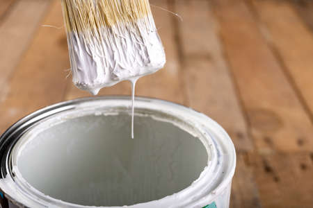 Brush dipped in white paint. Minor painting work at home. Light background.の写真素材