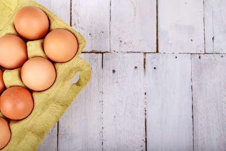 Fresh eggs in a cardboard form on a wooden table. Tasty eggs for baking bread in the bakery. Light background.の写真素材