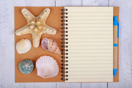 Notebook for writing your vacation memories. A blank sheet and seashells from the seaside. Light background.の写真素材