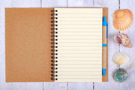 Notebook for writing your vacation memories. A blank sheet and seashells from the seaside. Light background.の写真素材