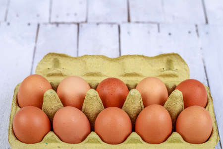 Fresh eggs in a cardboard form on a wooden table. Tasty eggs for baking bread in the bakery. Light...