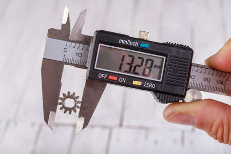Measure the diameter of the mode with an electronic caliper. Measuring accessories in a home workshop. Light background.の写真素材