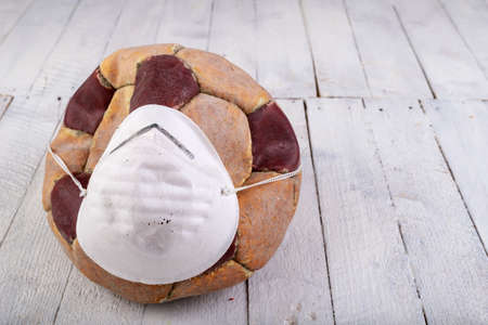 An old leather foot ball with a protective mask. Accessories for the game of football. Light background.の写真素材