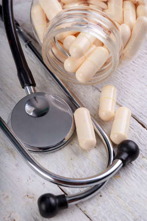 Medical pills and a stethoscope on the table. View of a pharmacist doctor's desk. Light background.の写真素材