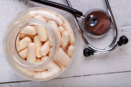 Medical pills and a stethoscope on the table. View of a pharmacist doctor's desk. Light background.の写真素材