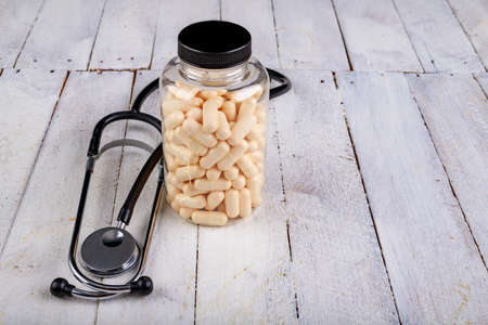 Medical pills and a stethoscope on the table. View of a pharmacist doctor's desk. Light background.の写真素材
