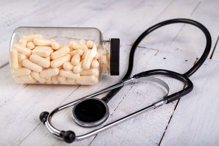 Medical pills and a stethoscope on the table. View of a pharmacist doctor's desk. Light background.