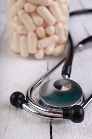 Medical pills and a stethoscope on the table. View of a pharmacist doctor's desk. Light background.の写真素材
