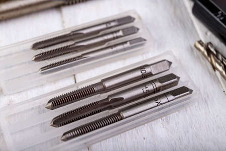 Metal taps prepared for work. Accessories in the locksmith's workshop. Light background.の写真素材