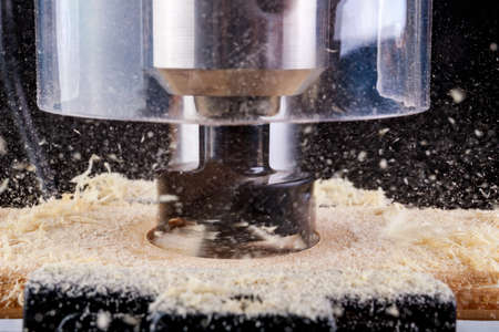Drilling in wood with a cup drill. Minor carpentry work in a home workshop. Dark background.の写真素材