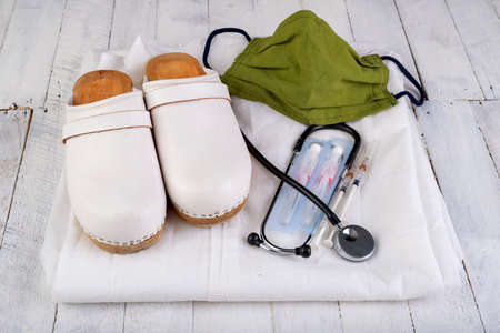 Working clothes for a medic. Medical accessories on a white table. Light background.の写真素材