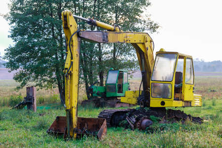 Old dilapidated trencher standing in a meadow. Faulty construction accessories. Autumn season.の写真素材