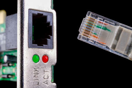 Rj45 cable and network card slot. Cable for data transmission in a computer network. Dark background.の写真素材