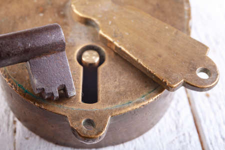 Old brass padlock and metal dark key. Old anti-theft security methods. Light background.の写真素材