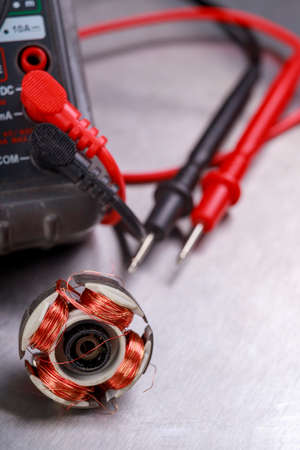 Damaged electric motor rotor and electric meter. Measurement work in an electrical workshop. Metallic background.の写真素材
