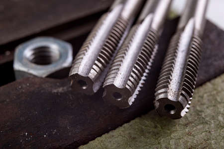 Threading a metal nut in a vice. Minor locksmith work in the workshop. Light background.の写真素材