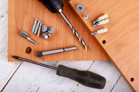 Joining chipboards with the use of specialized metal connectors. Minor carpentry work in the workshop. Light background.の写真素材