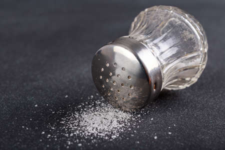 Glass salt shaker with metal cap, Kitchen accessories for seasoning dishes. Dark background.の写真素材
