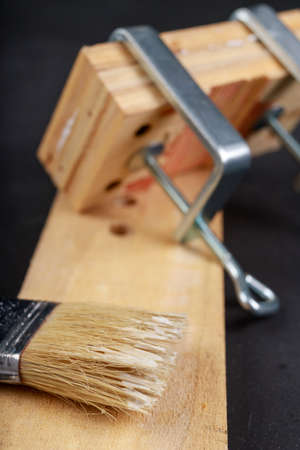 Gluing pieces of wood with carpentry glue. Minor carpentry work in the workshop. Dark background.の写真素材