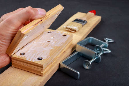 Gluing pieces of wood with carpentry glue. Minor carpentry work in the workshop. Dark background.の写真素材
