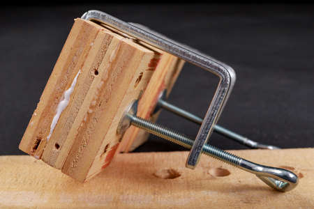 Gluing pieces of wood with carpentry glue. Minor carpentry work in the workshop. Dark background.の写真素材
