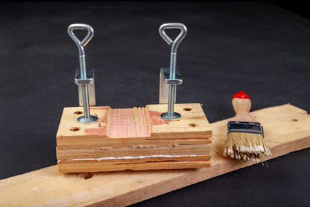 Gluing pieces of wood with carpentry glue. Minor carpentry work in the workshop. Dark background.の写真素材
