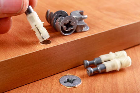 Joining chipboards with the use of specialized metal connectors. Minor carpentry work in the workshop. Light background.の写真素材