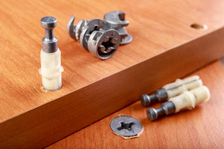 Joining chipboards with the use of specialized metal connectors. Minor carpentry work in the workshop. Light background.の写真素材