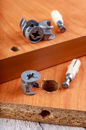 Joining chipboards with the use of specialized metal connectors. Minor carpentry work in the workshop. Light background.の写真素材