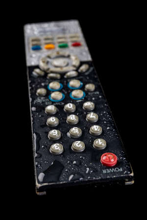 TV remote control with water drops. Water-poured electronic device. Dark background.の写真素材