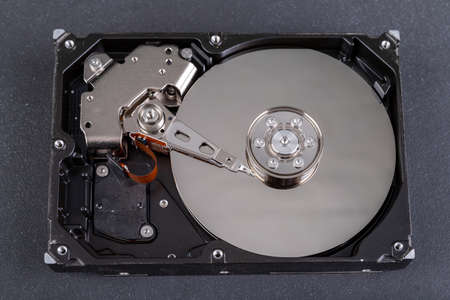 Open old computer disk on the table. Computer head and data carrier. Dark background.の写真素材