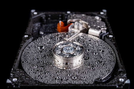 Wet old computer disk on the table. Head and computer data carrier wetted with water. Dark background.の写真素材