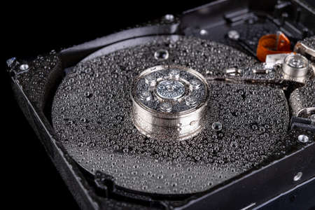 Wet old computer disk on the table. Head and computer data carrier wetted with water. Dark background.の写真素材