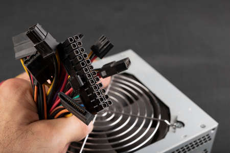 Hand held plugs for powering PC components. Components of the computer power supply. Dark background.の写真素材