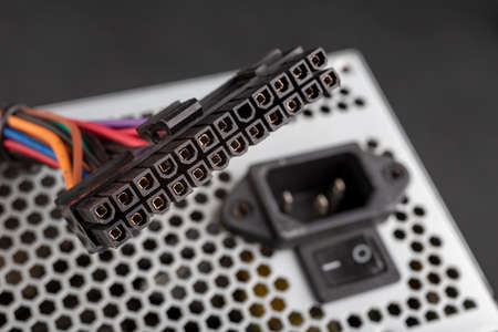 Large plug to power the PC motherboard. Components of the computer power supply. Dark background.