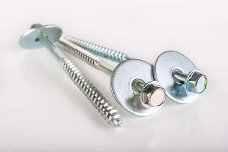 Long nickel-plated wood screws with washers. Metal accessories for joining wooden elements. Light background.の写真素材