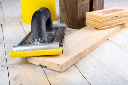 Sanding wood with sandpaper. Carpentry accessories for precise woodworking. Light background.の写真素材