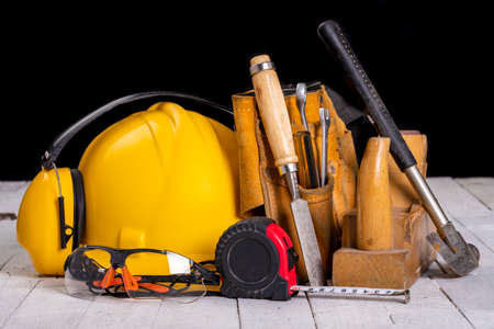 Carpentry tools and a protective helmet. Accessories for work in a home workshop. Dark background.の写真素材