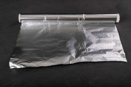 Aluminum foil wound on a cardboard roller. Material used to store food. Dark background.の写真素材