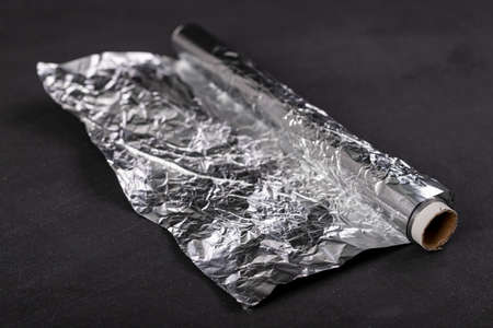 Aluminum foil wound on a cardboard roller. Material used to store food. Dark background.の写真素材